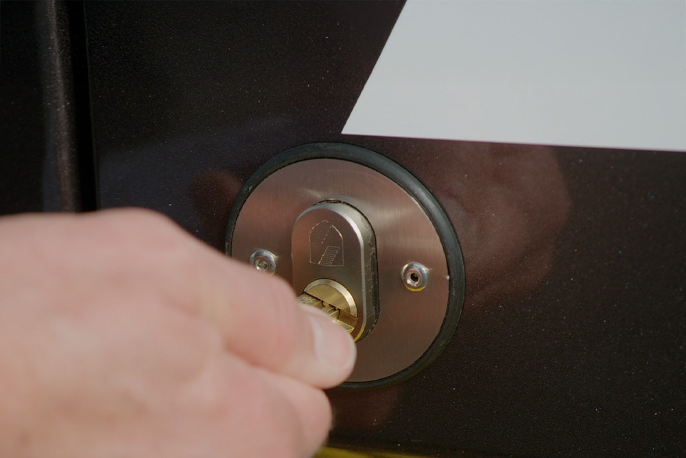 Hand verriegelt eine Transporter-Tuer mit Schluessel.  