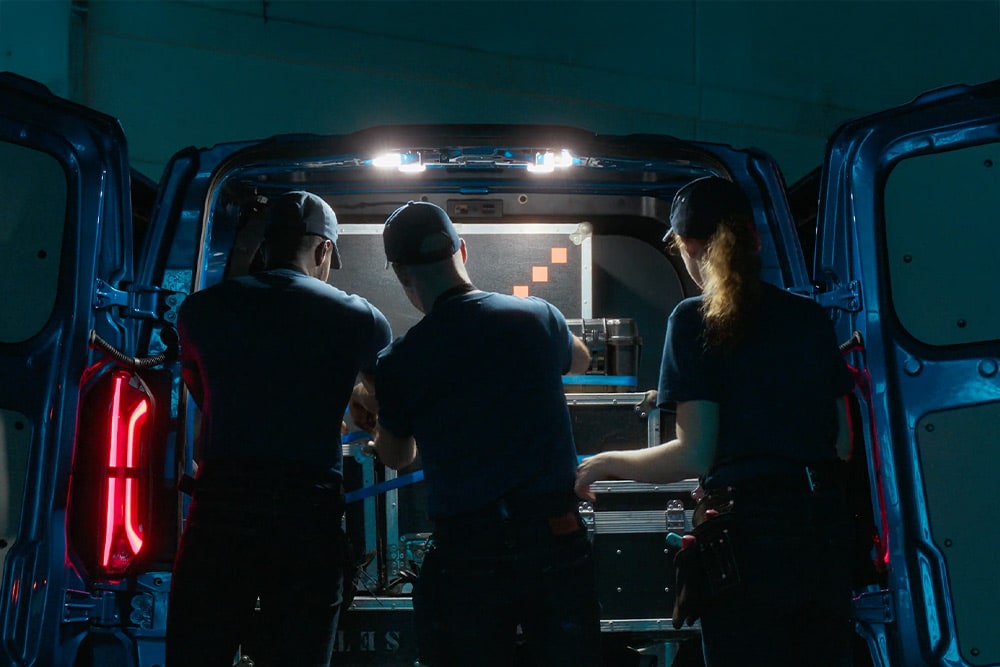 Drei Personen arbeiten im Laderaum eines Ford E-Transit Custom Elektro-Transporters.