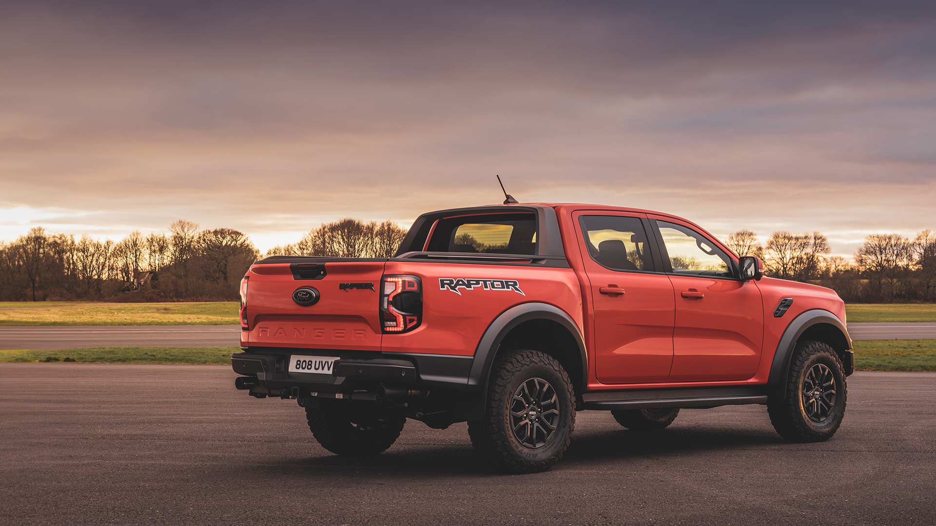 Heckansicht eines Code Orange Ford Ranger Raptor während der Fahrt auf einer Rennstrecke.