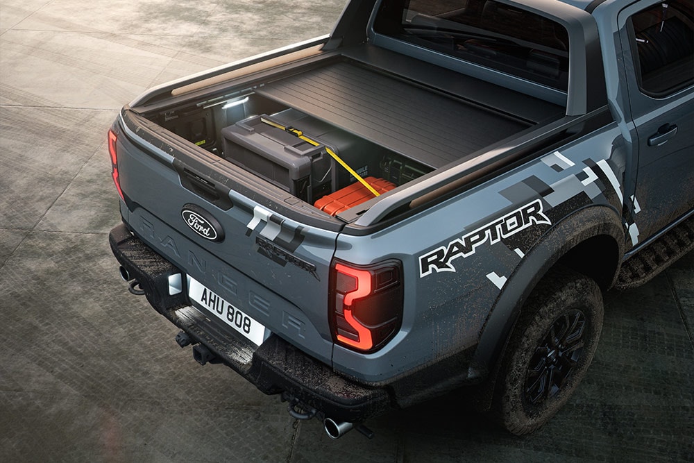 Rückansicht eines geparkten blauen Ranger Raptor mit hervorgehobenem elektrisch betriebenem Rollladen.