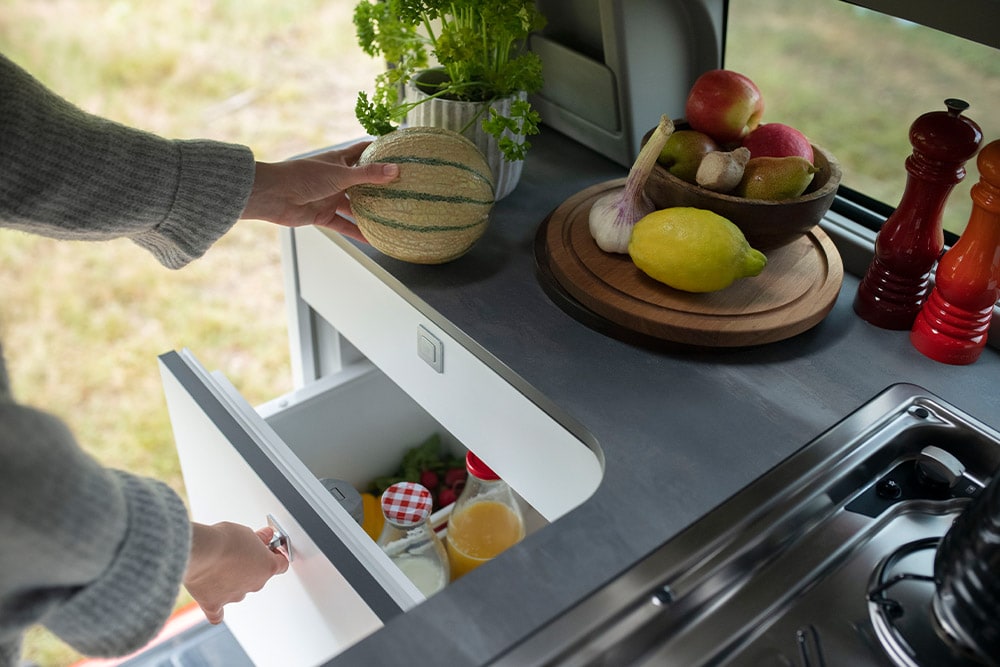 Ford Transit Custom Nugget integrated 33L drawer fridge with fruit on the counter.