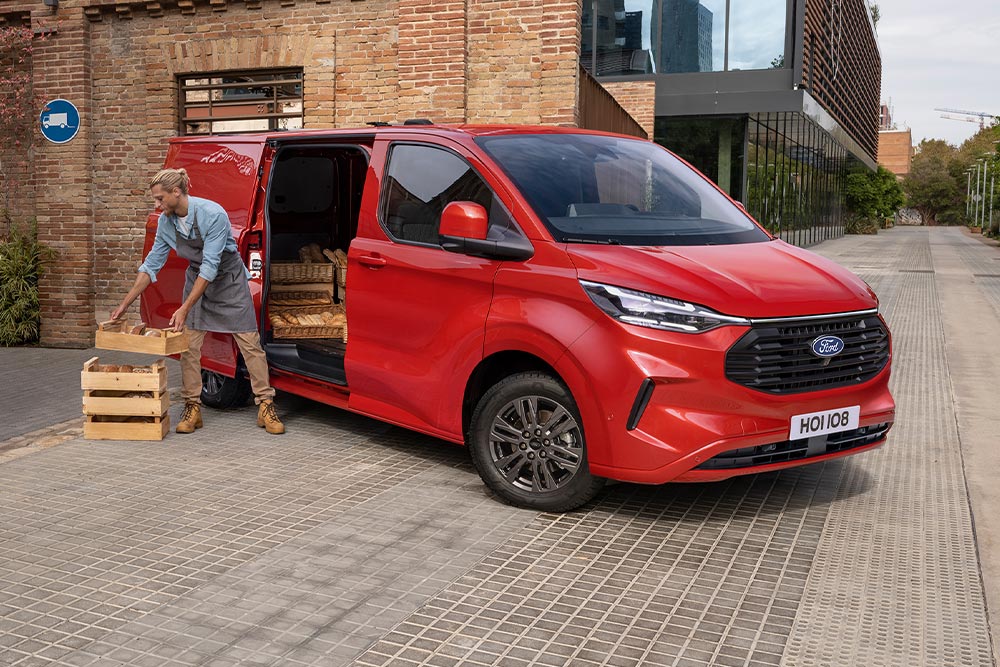 Zusteller laedt Pakete in einen roten Ford Transit Custom