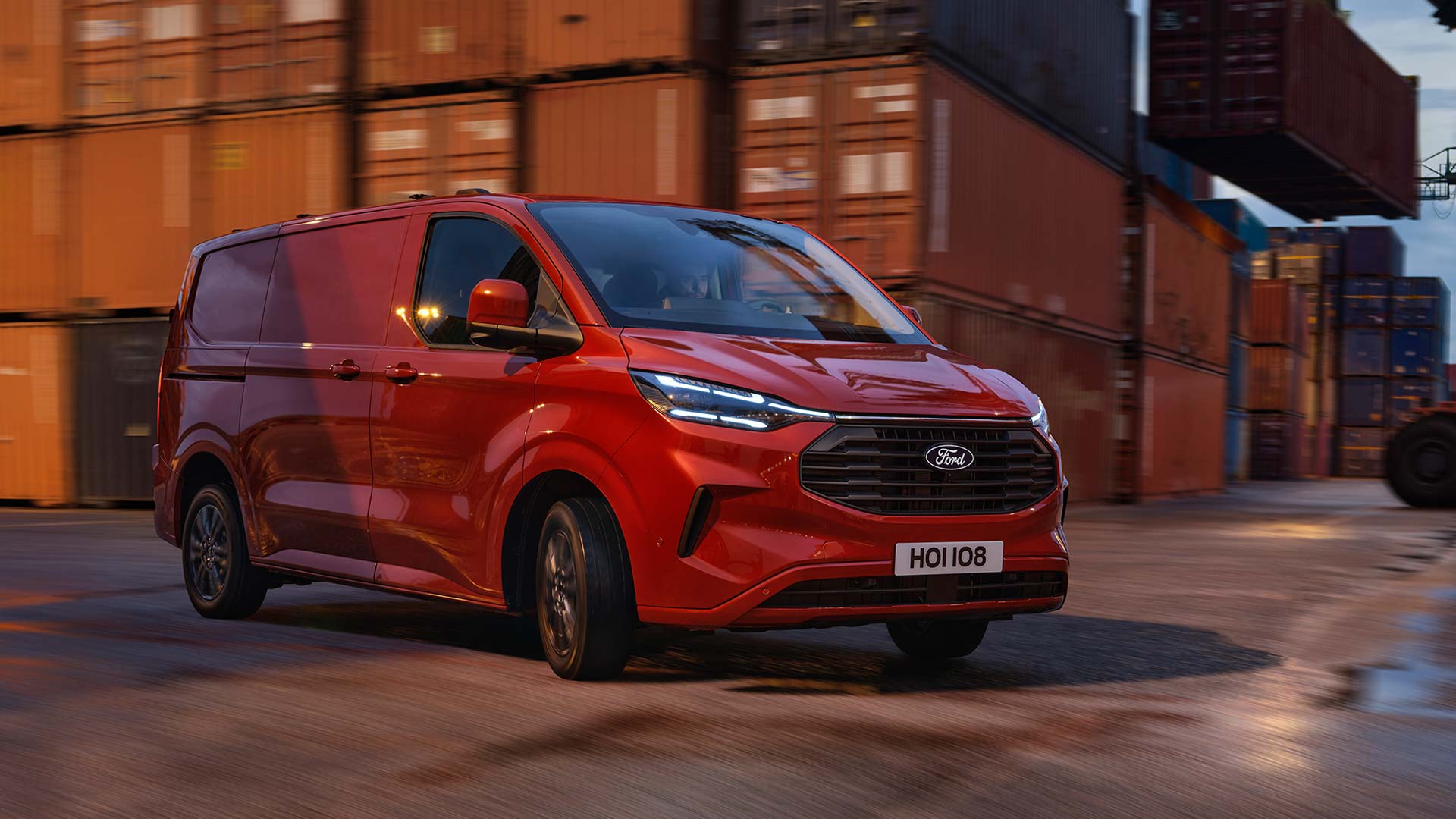 Roter Ford Transit Custom Kleintransporter faehrt durch einen Hafenbereich