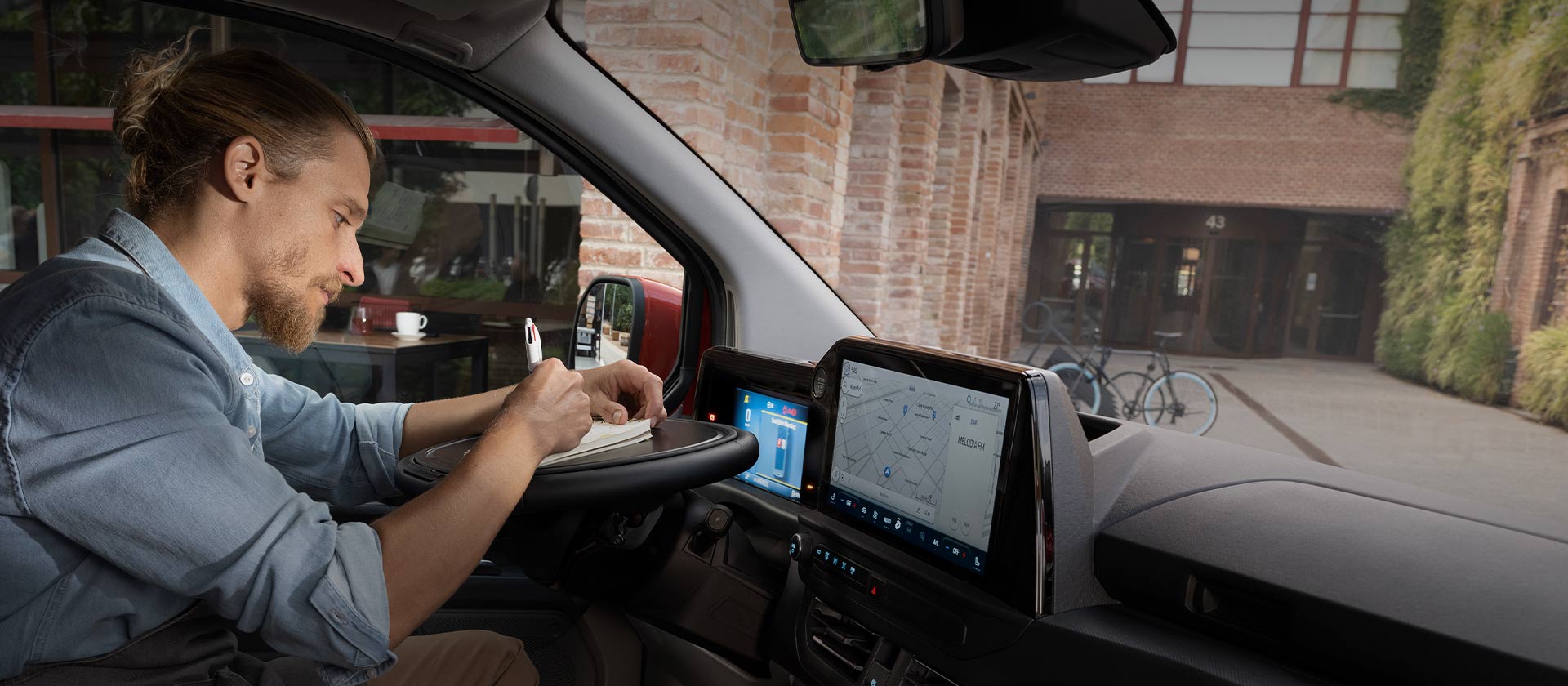 Person schreibt in einem Notizbuch im Ford Transit Custom
