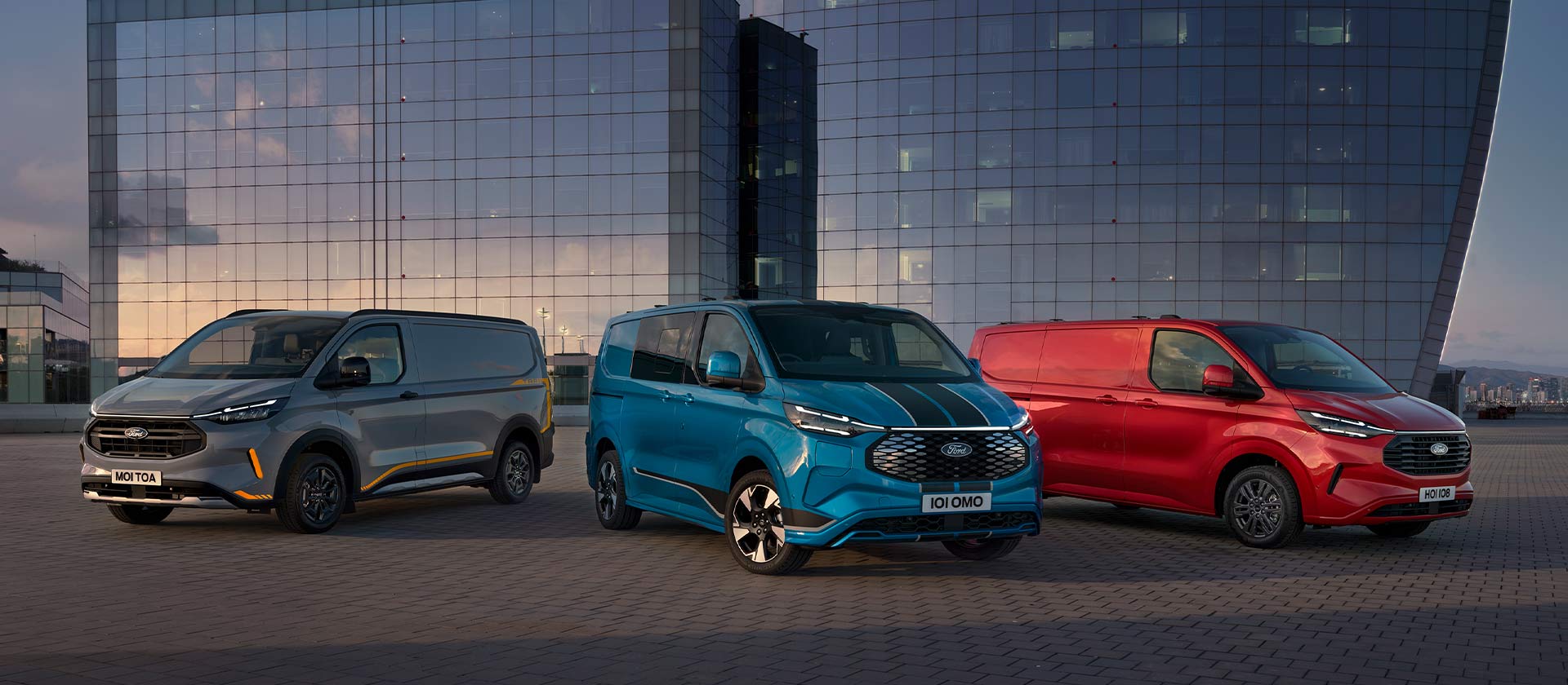 Drei Ford Transit Custom Sport Vans in Grau, Blau und Rot geparkt