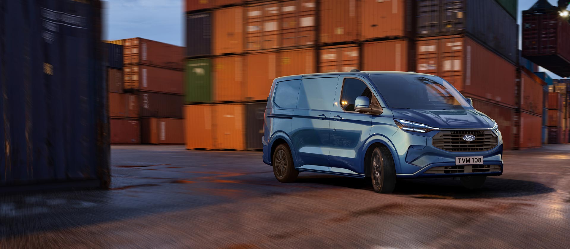 Blauer  Ford Transit Custom Kleintransporter faehrt durch einen Hafenbereich