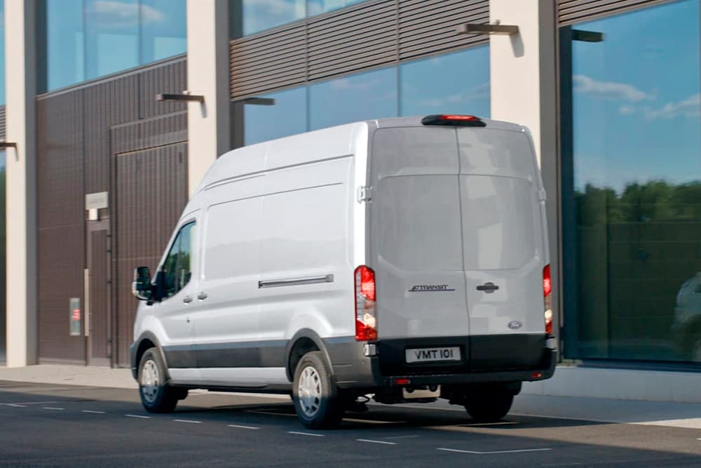 Rückansicht eines weißen Ford Transit, der auf einer Straße geparkt ist.