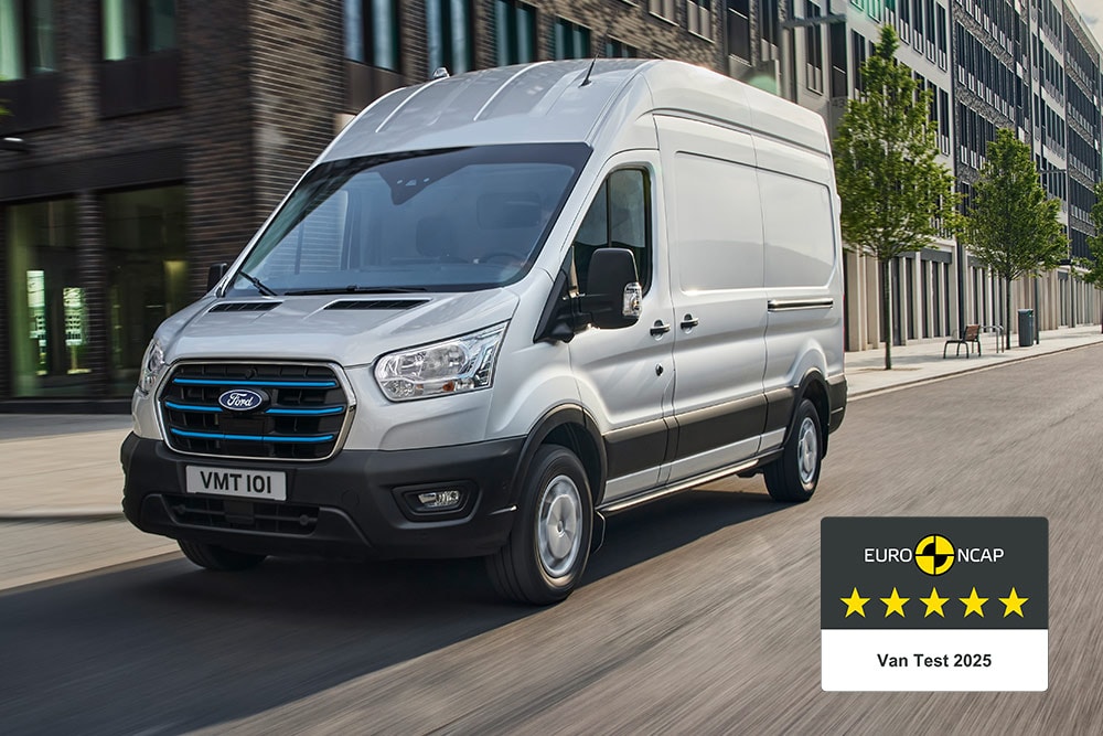 Silberner Ford E-Transit  Kastenwagen, der auf einer Straße fährt, mit dem Abzeichen „Gold 2022 Commercial Kastenwagen Safety“.