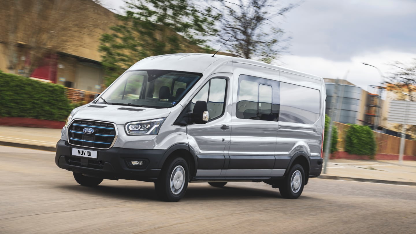 Elektrischer Ford E-Transit Doppelkabine Silber fährt auf Straße zur Arbeit