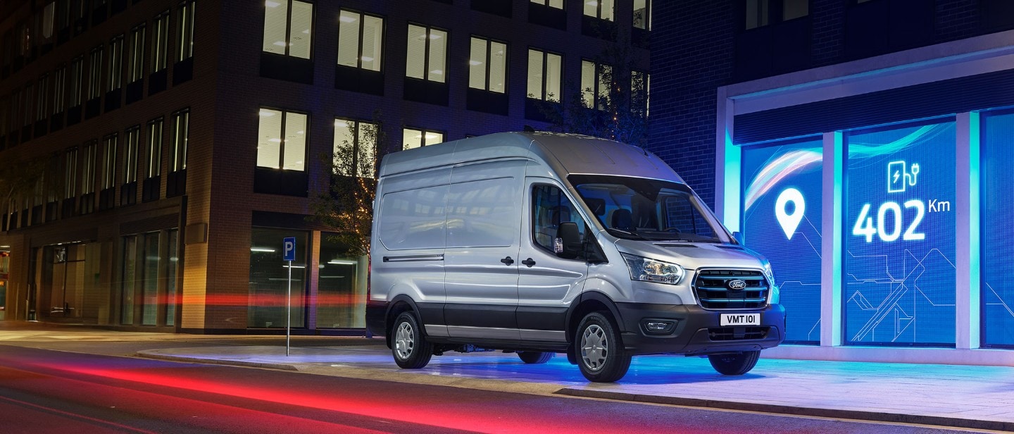 New E-Transit side view with the backdrop of city in night with blue electric lights