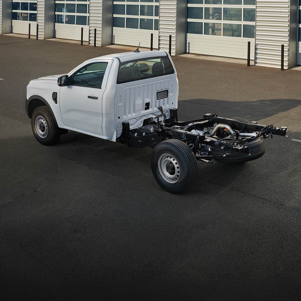 Ein Ford Ranger mit weißem Fahrgestell geparkt vor einer Reihe von Garagentoren.