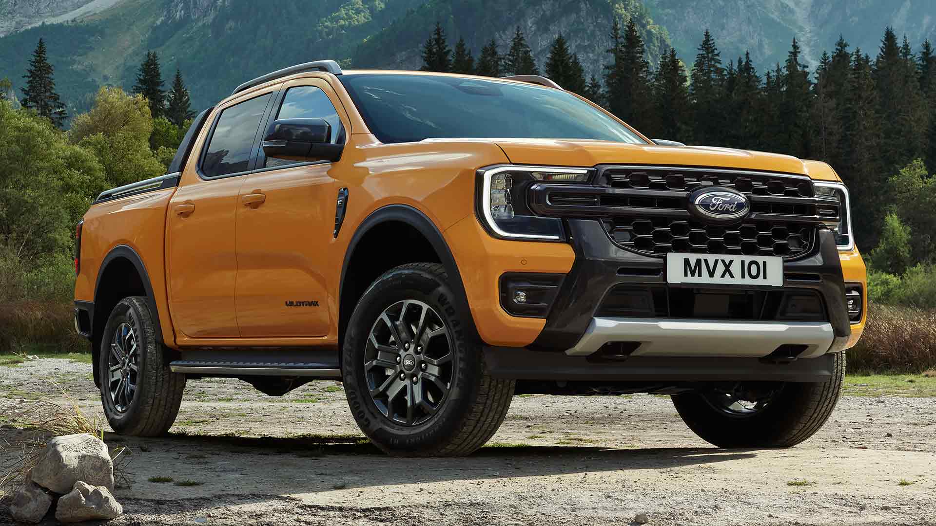 Gelber Ford Ranger Wildtrak Doppelkabine vor malerischer Wald- und Gebirgskulisse.