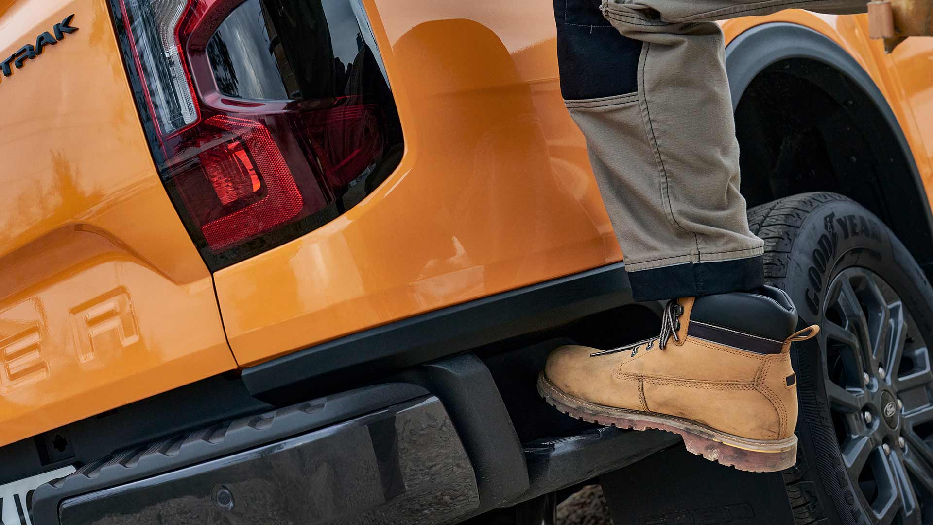 Arbeiter, der auf die integrierte hintere Stufe des Ford Ranger tritt.