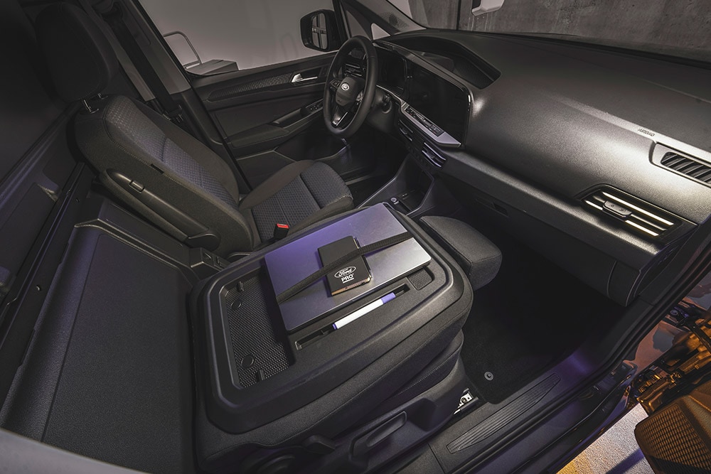 Interieur des Ford Transit Connect mit Armaturenbrett, Sitzen, einem Laptop und einem Smartphone auf der Mittelkonsole.