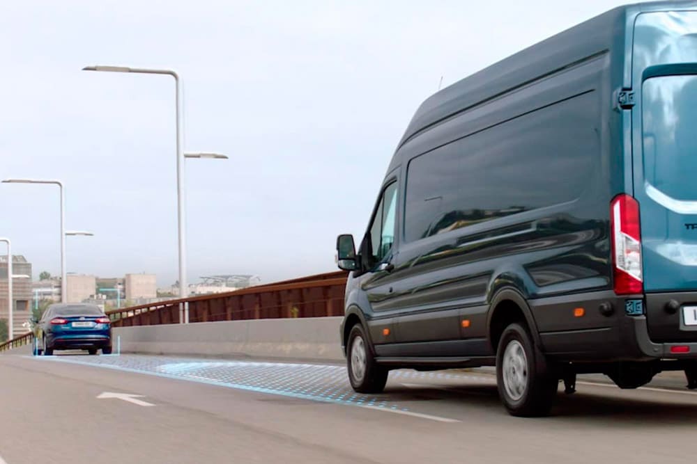 Blauer Ford Transit Kastenwagen mit blauen Linien auf der Fahrbahn zur Darstellung der Fahrerassistenzsysteme.