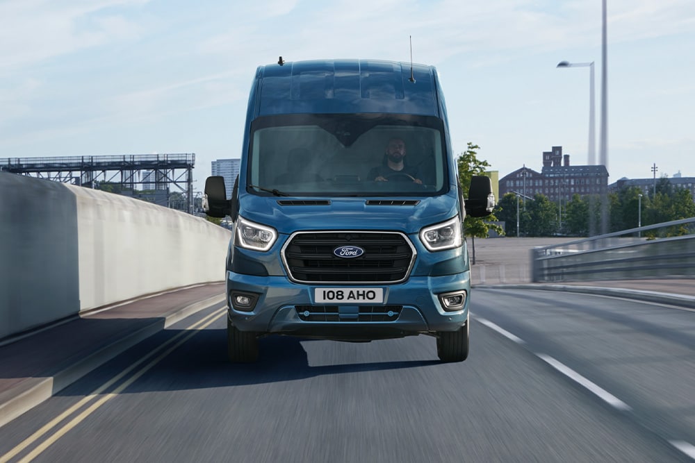 Frontansicht eines blauen Ford Transit Kastenwagen bei der Fahrt auf einer Straße.
