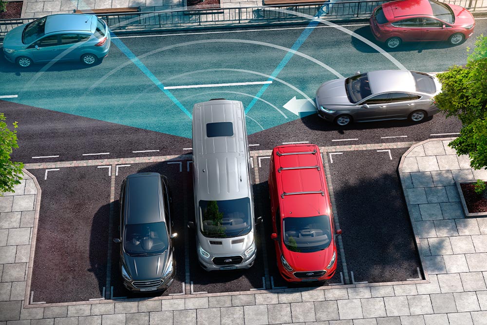 Ein silberfarbener Ford Transit Kastenwagen beim Rückwärtsfahren; blaue Linien visualisieren den Erfassungsbereich der Parksensoren.