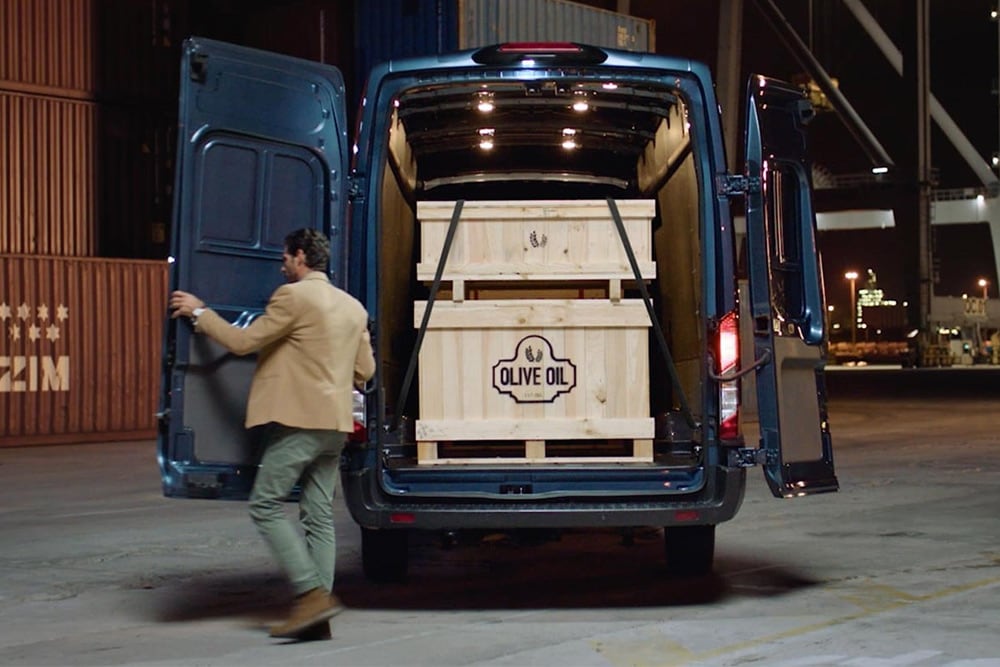 Ford Transit Kastenwagen mit geöffneter Hecktüre und Ladegut im Innenraum.