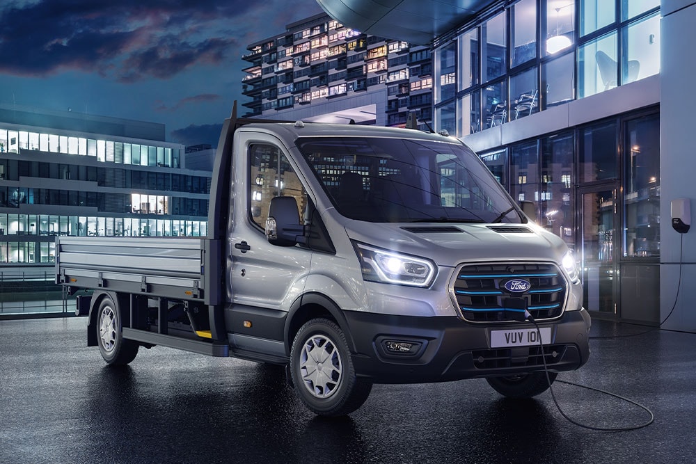 Ford Transit Fahrgestell in Silber bei Nacht vor einem modernen Gebäude geparkt.
