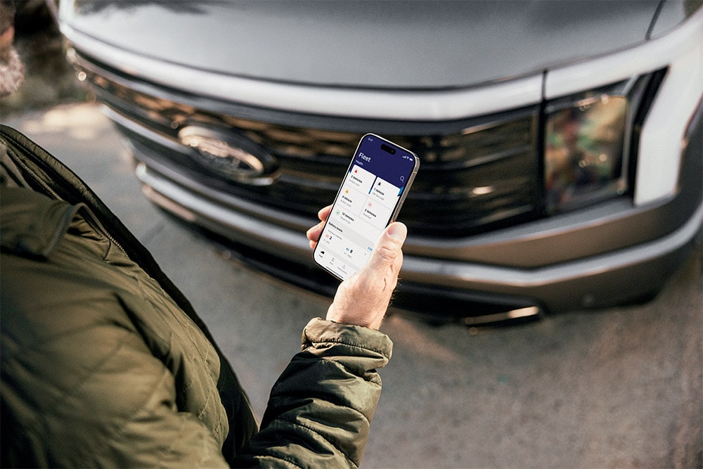 Ein Mann schaut auf sein Smartphone vor einem Ford Ranger.