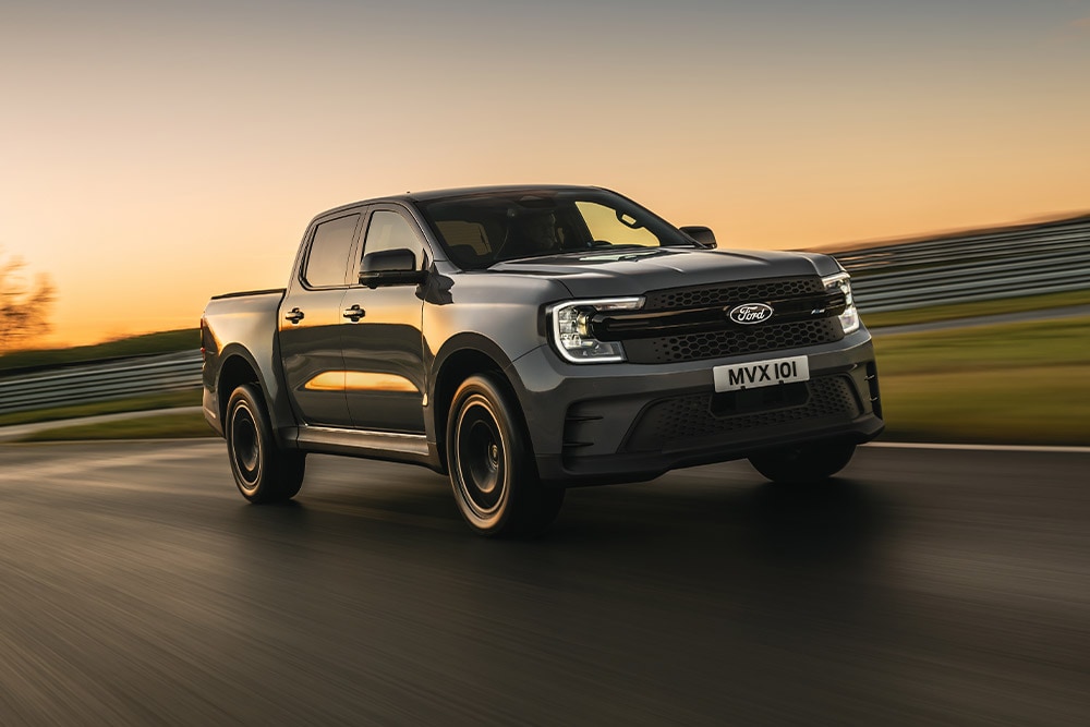 Ein dunkelgrauer Ford Ranger Platinum fährt bei Sonnenuntergang auf einer Strecke.