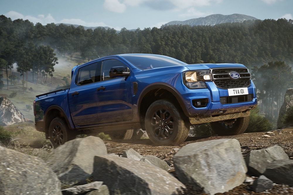 Ein blauer Ford Ranger Pick-up fährt auf einer unbefestigten Straße durch einen Wald und hinterlässt eine Staubspur.