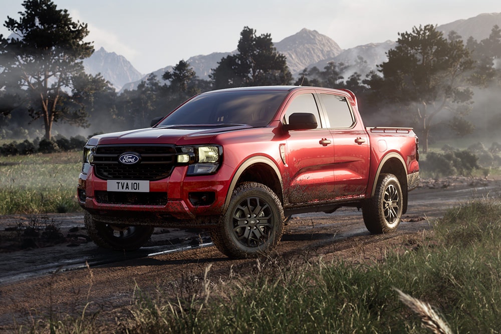 Ein roter Ford Ranger Raptor fährt auf einer unbefestigten Straße durch eine malerische Landschaft.