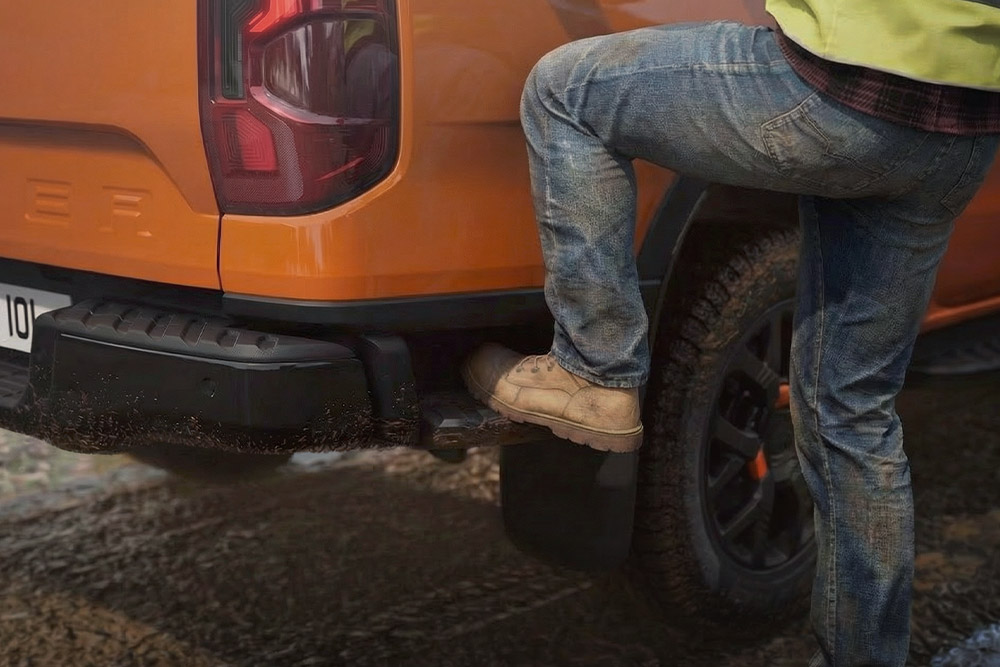 Ein Arbeiter tritt auf die integrierte hintere Stufe des Ford Ranger Wildtrak.