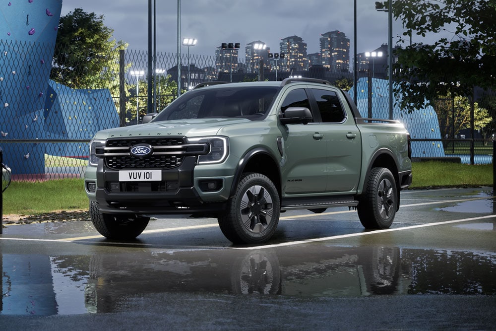 Grauer Ford Ranger PHEV, der in der Abenddämmerung vor einer Stadtkulisse steht.