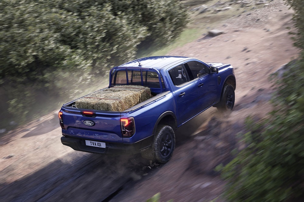 Draufsicht von hinten auf einen blauen Ford Ranger, der auf einer unbefestigten Straße fährt.