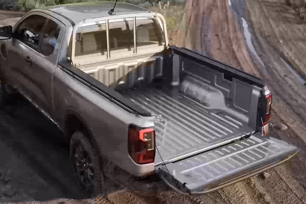 Silberner Ford Ranger XLT mit Extrakabine und geöffneter Heckklappe auf schlammigem Untergrund, von oben gesehen.