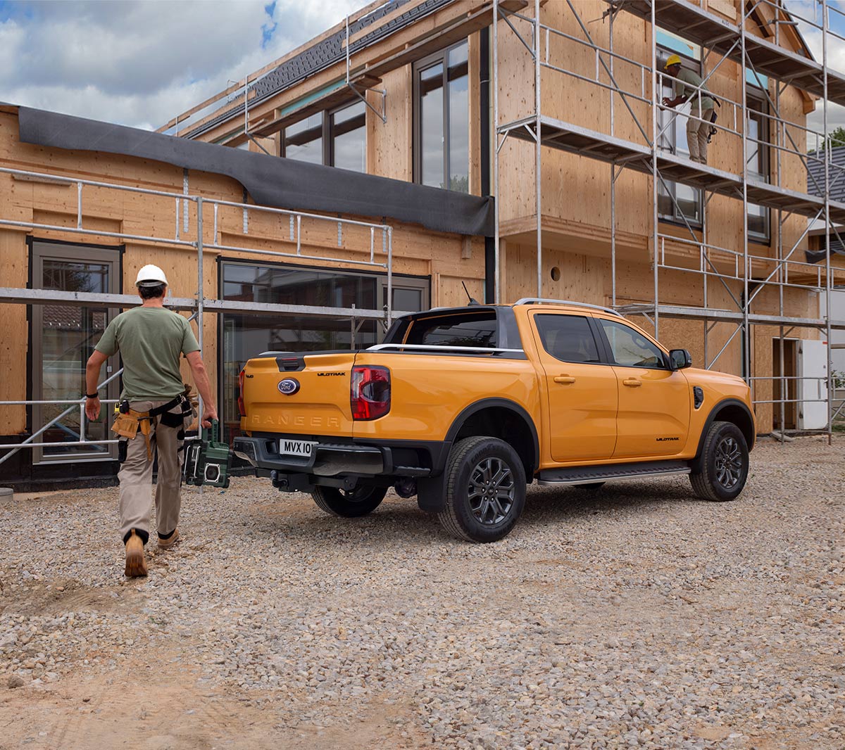 Ford Ranger in Orange in der ¾-Seitenansicht parkt vor Wohnhausneubau