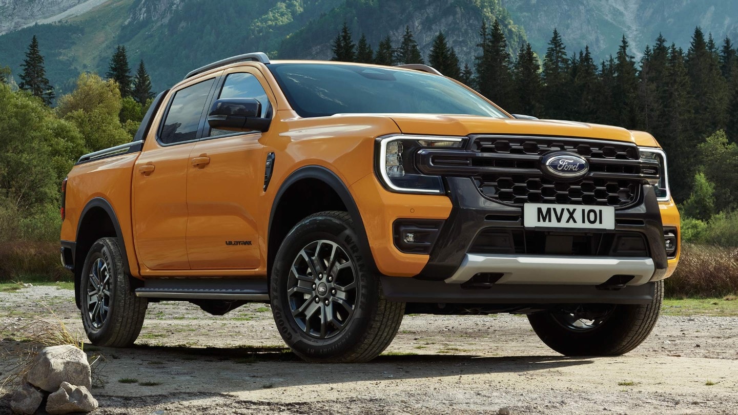 Ford Ranger in Orange in der ¾-Frontansicht parkt auf unbefestigtem Gelände im Gebirge