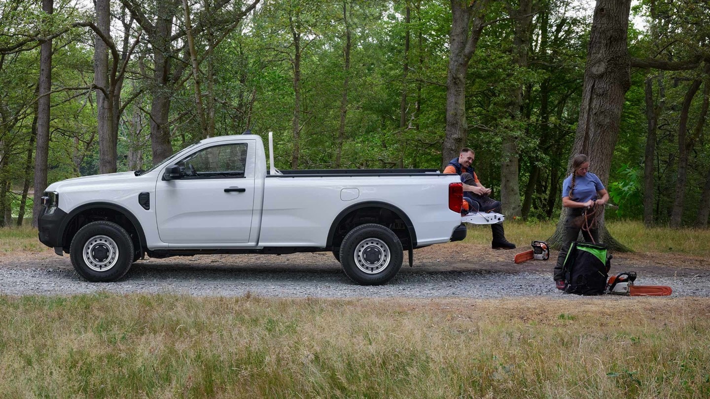 Ford Ranger in Weiß in der Seitenansicht parkt auf Waldweg neben Waldarbeitern