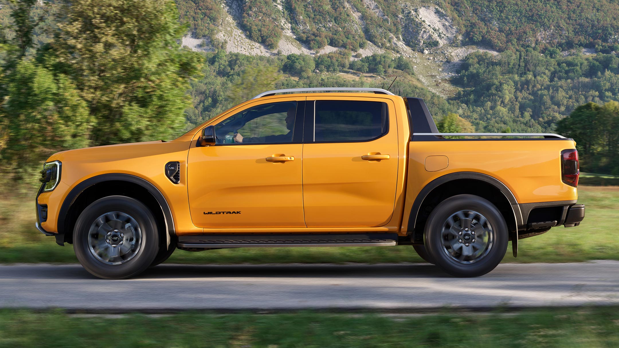 Ford Ranger in Orange in der Seitenansicht fährt durch Gebirgslandschaft