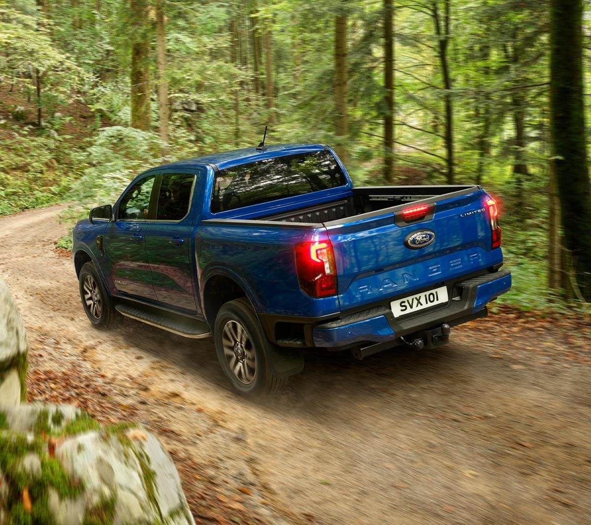 Ford Ranger in Blau in der ¾-Heckansicht fährt auf Waldweg