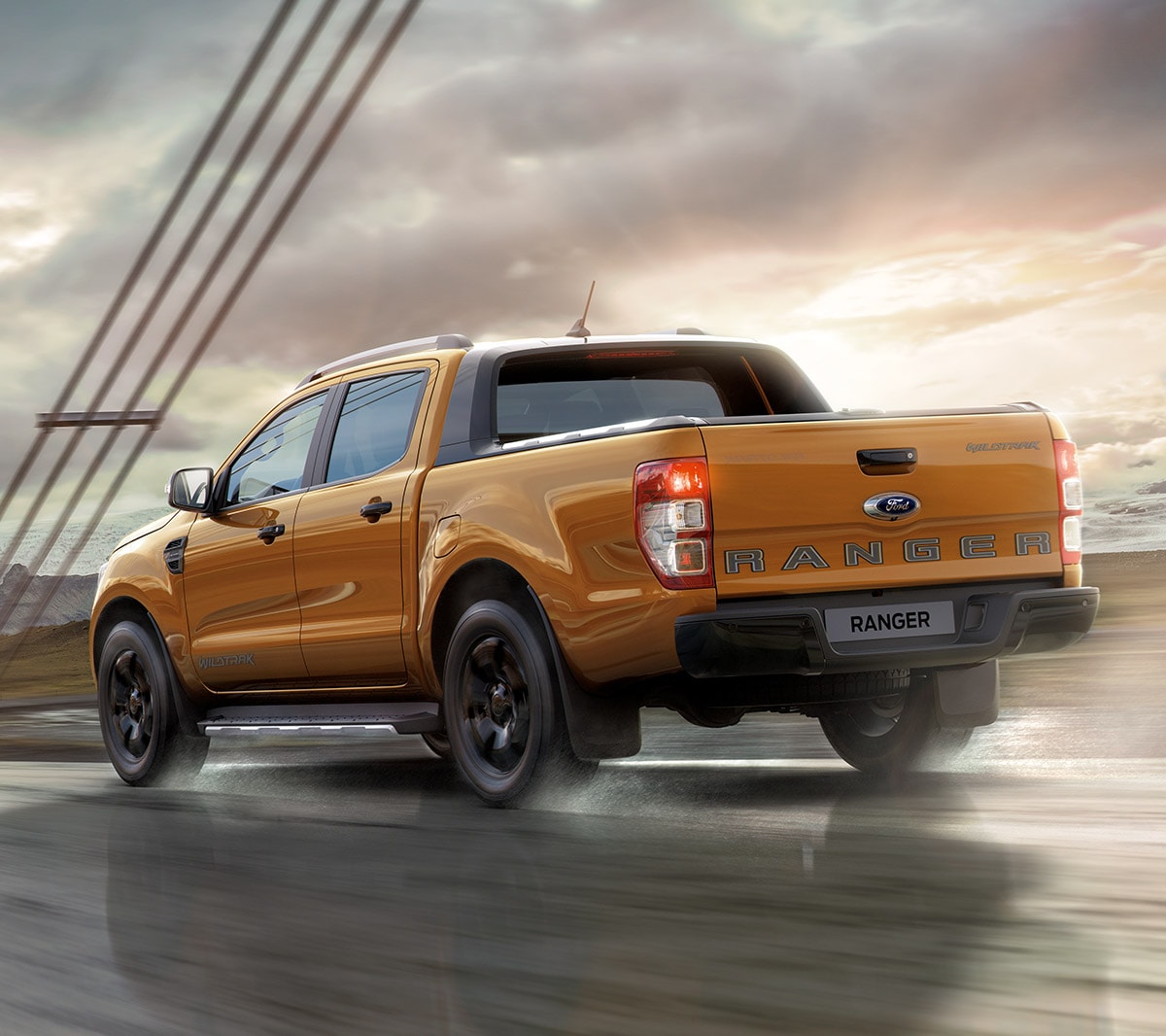 Ford Ranger Orange ¾-Heckansicht in Bewegung auf Brücke