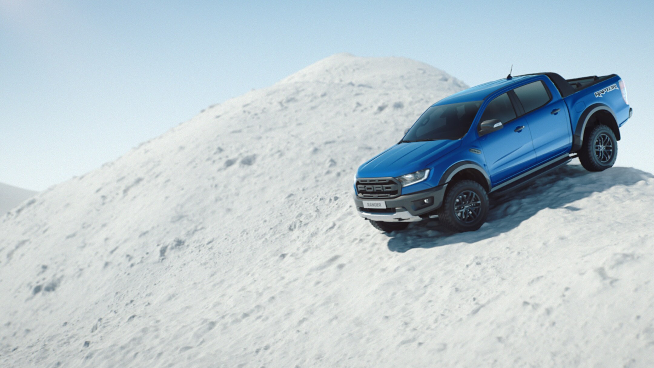 Ford Ranger Blau ¾-Seitenansicht bergab in Bewegung auf schneebedeckter Bergkuppe