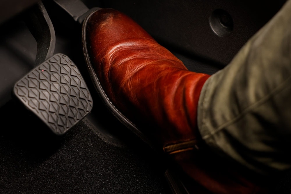 Ein Fuß in einem braunen Stiefel betätigt das Gaspedal eines Ford Fahrzeugs.