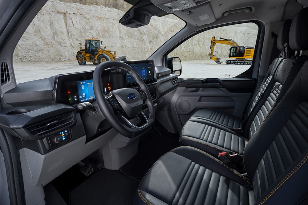 Innenansicht eines Ford Transit Custom Transporters mit Armaturenbrett, Lenkrad und Sitzen.