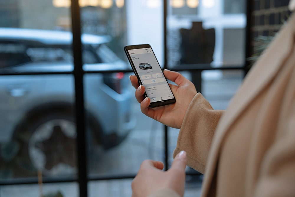 Eine Person hält ein Smartphone, auf dem die Ford-App mit Flottenmanagement-Informationen angezeigt wird.