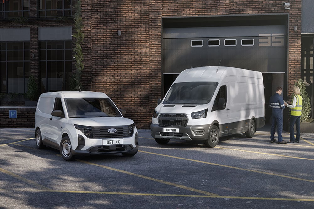 Zwei weiße Ford-Transporter, die vor einem modernen Gebäude geparkt sind, zwei Personen unterhalten sich neben den Fahrzeugen.
