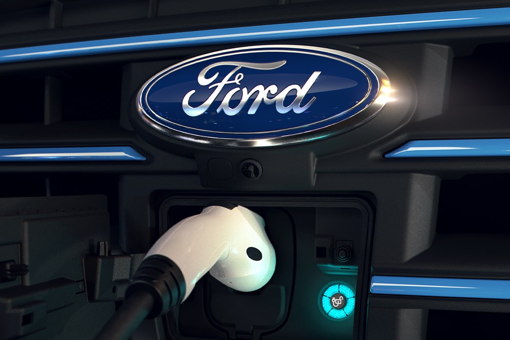 Nahaufnahme eines weißen Ladekabels, das in den vorderen Ladeanschluss eines Ford-Elektrofahrzeugs eingesteckt ist.