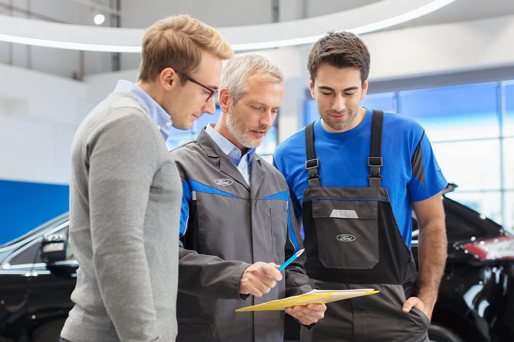 Drei Experten besprechen sofort verfügbare Fahrzeugoptionen in einem Ford Transit Centre.