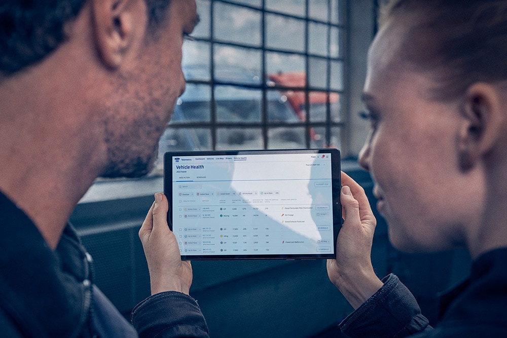 Flottenmanager betrachten Fahrzeugtelematik auf einem Tablet.