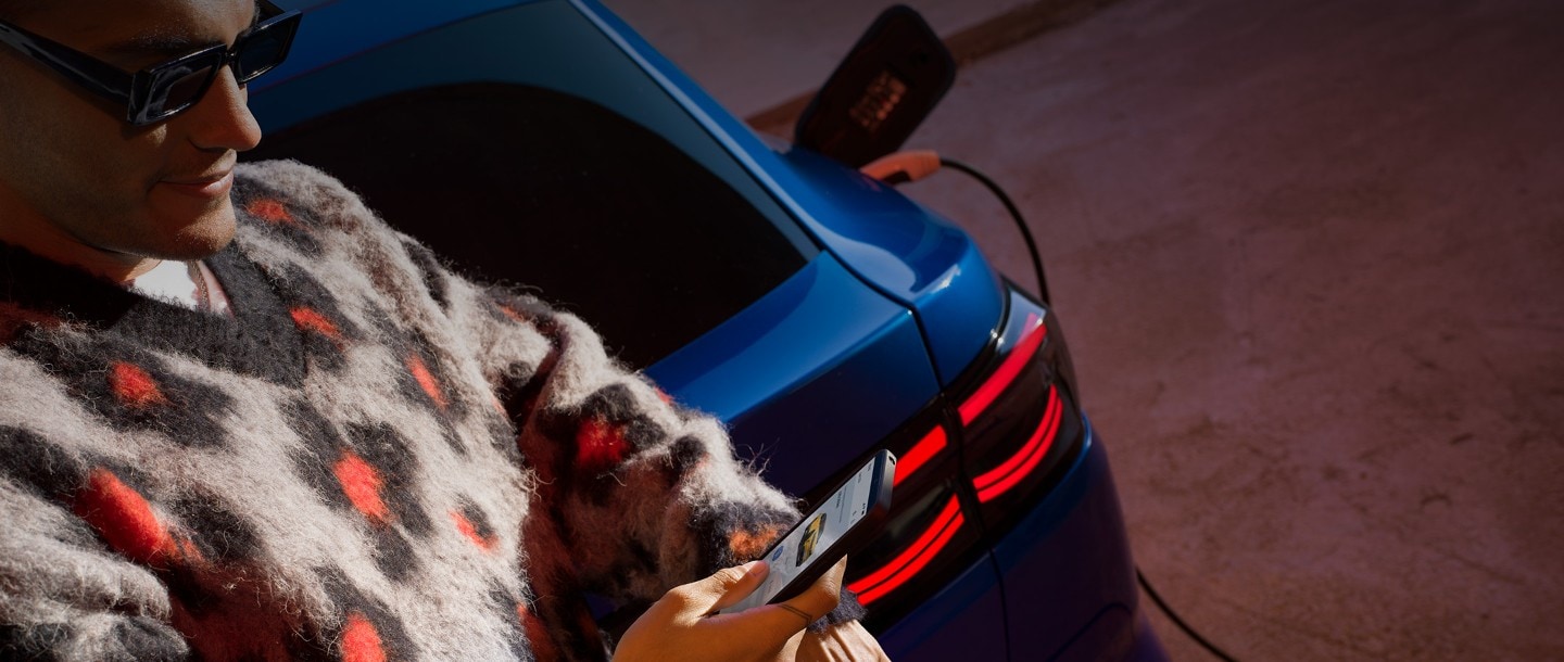 Mann mit Smartphone nutzt mobile App neben Ford EcoSport