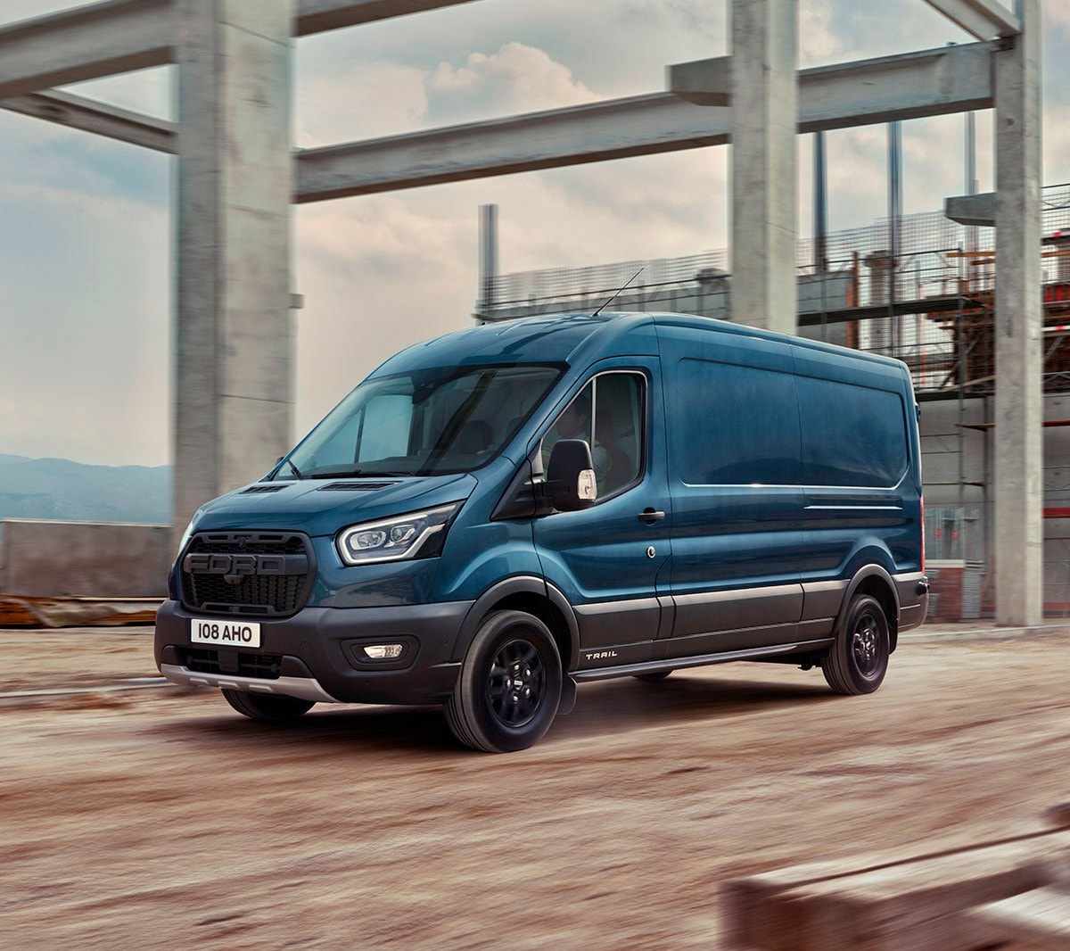 Ford Transit in Blau in der Seitenansicht über eine Baustelle fahrend