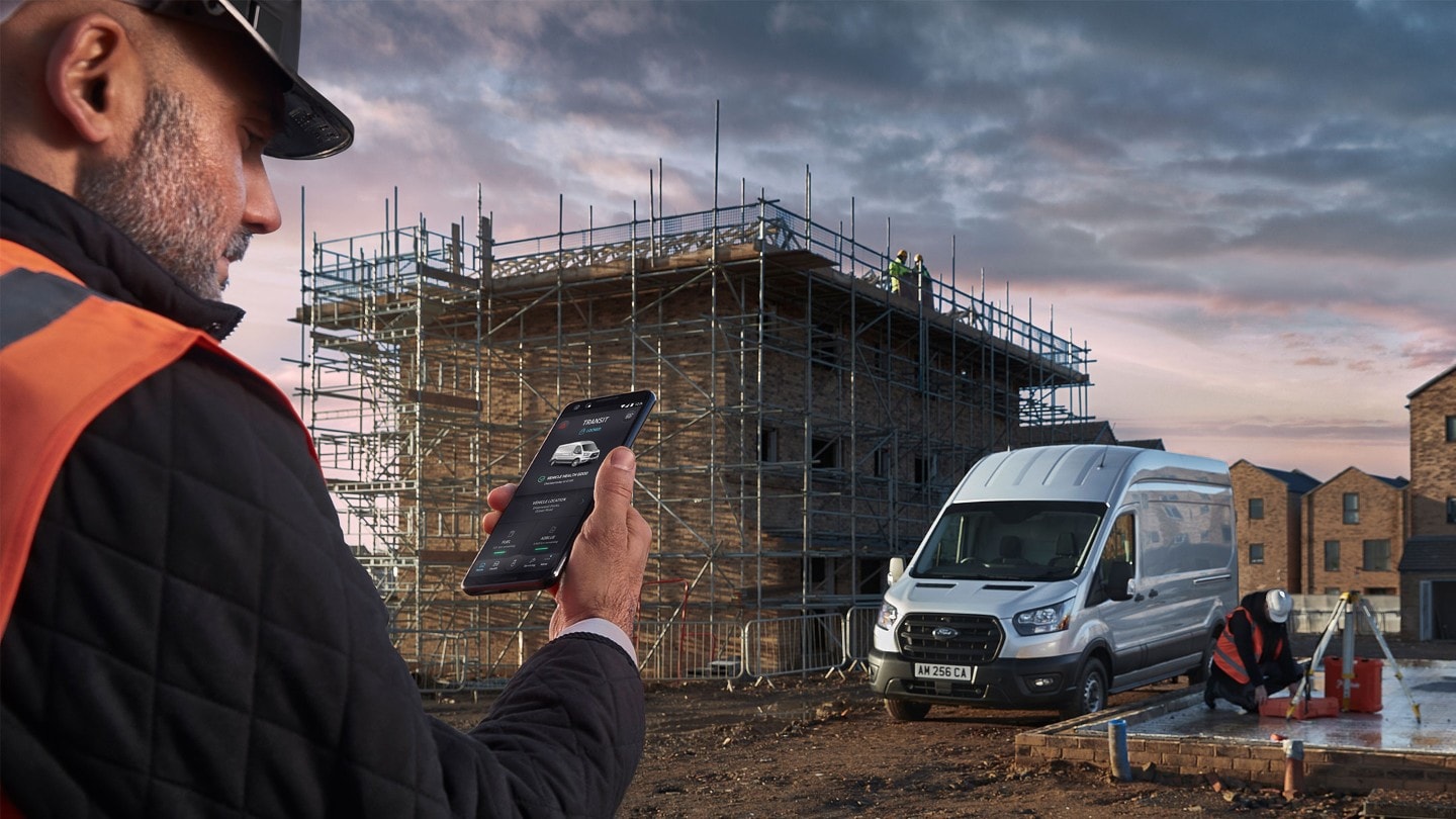 Mann hält auf Baustelle mobiles Telefon in der Hand
