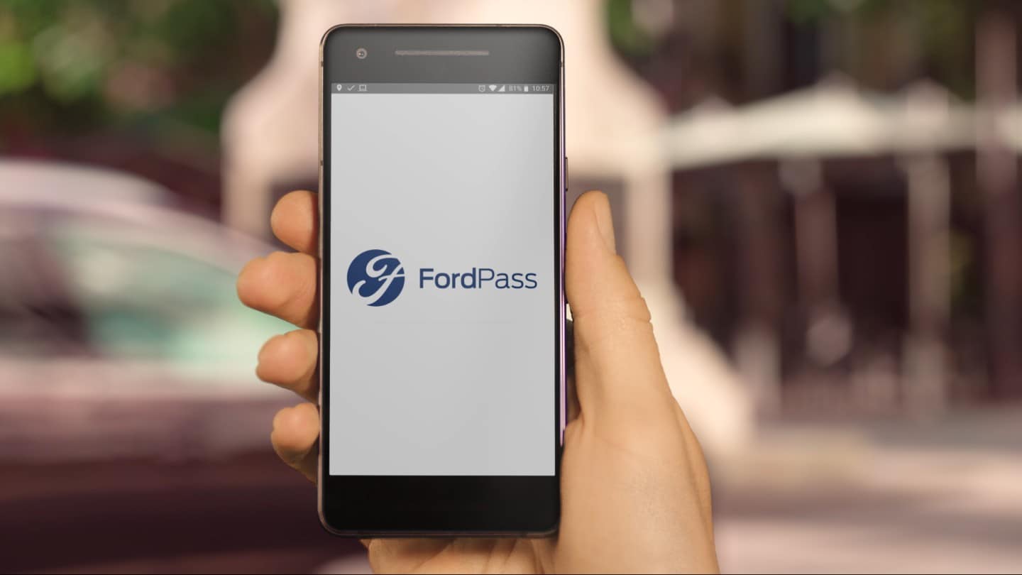 Detailansicht einer Hand, die ein Smartphone mit FordPass App hält
