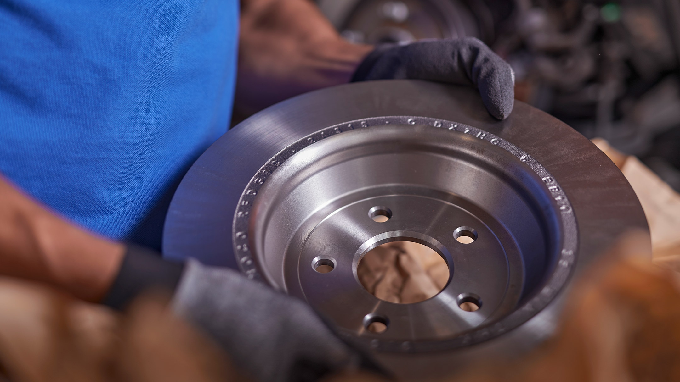 Ein Ford Mechaniker hält eine originale Ford Bremsscheibe in den Händen. 